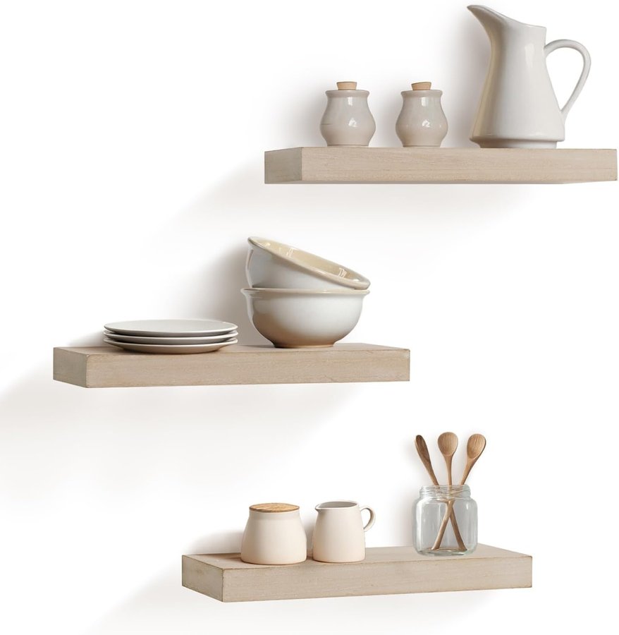 Three rustic wood-tone ledge floating shelves styled with cream ceramics